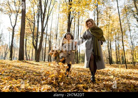 Una ragazza e una madre giocose che si divertono nel parco autunnale Foto Stock