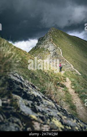 Donna con zaino per cani sul Klomnockweg in direzione nord, tra Mallnock e Klomnock con vista sul Klomnock, Nockberge Biosphere Park, Carinth Foto Stock