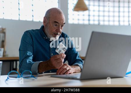 Uomo anziano che prende il consiglio medico sulla videochiamata con il medico nel paese Foto Stock