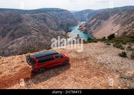 Viaggio su strada Croazia, camper su un campo con vista, due persone che guardano verso il basso nella valle Foto Stock