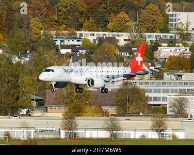 Helvetic Airways Embraer 190-E2 aereo che atterra all'aeroporto di Zurigo. Colori autunnali dietro l'aereo E190 della Helvetic Airline che arriva all'aeroporto di Kloten. Foto Stock