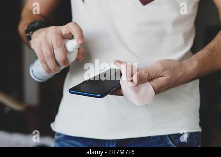 un uomo schizza su un panno da un igienizzatore per disinfettare e prevenire le malattie virali. Agente antibatterico antimicrobico per l'uccisione di microbi. Pulizia di un Foto Stock