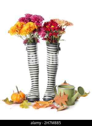 Composizione con stivali in gomma, fiori bellissimi e foglie autunnali su sfondo bianco Foto Stock