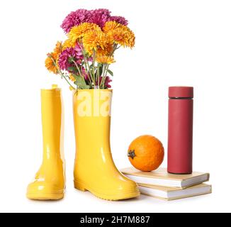 Stivali in gomma con fiori, thermos, libri e zucca su sfondo bianco Foto Stock