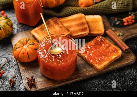 Ciotola di marmellata di zucca dolce con toast su sfondo nero Foto Stock