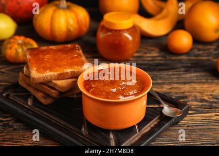 Ciotola di marmellata di zucca dolce con toast su sfondo di legno Foto Stock