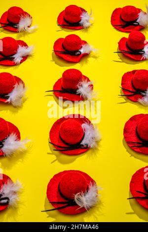 Quindici cappelli di lana feltrati con una piuma su sfondo giallo Foto Stock