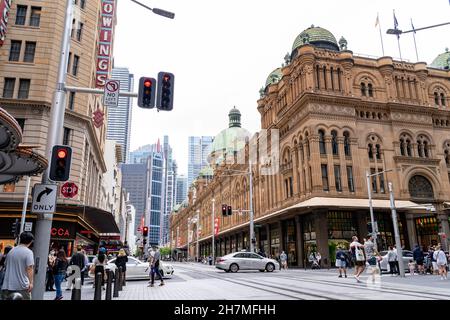 Vista sulla strada della folla di persone che attraversano binari ferroviari leggeri nel quartiere Centrale degli Affari vicino all'edificio Queen Victoria Sydney, Australia, 20 Nov 2021. Foto Stock