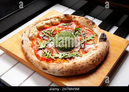 Pizza al prosciutto di Parma, rucola e burrata al pesto verde. Un piatto gustoso. Fotografia culinaria. Suggerimento di servire il piatto. Foto Stock