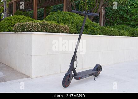 Scooter elettrico nero parcheggiato sulla strada. Foto Stock