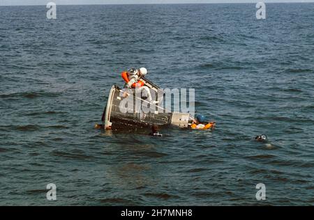 (15 ottobre 1965) --- Astronauta James A. Lovell Jr., pilota dell'equipaggio principale per il faro spaziale Gemini-7, siede sopra l'articolo di prova statico dell'astronauta Gemini durante l'addestramento di uscita dell'acqua nel Golfo del Messico. L'astronauta Frank Borman (che indossa il casco blu), pilota di comando dell'equipaggio principale, è appeso al naso della navicella. I subacquei della NASA sono in acqua come precauzione di sicurezza Foto Stock