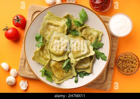 Delizioso concetto di cibo con ravioli su sfondo arancione Foto Stock