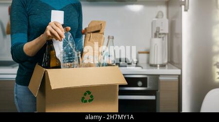 smistamento rifiuti domestici - donna che inserisce la bottiglia di plastica nel cestino per rifiuti riciclati a casa. spazio copia Foto Stock