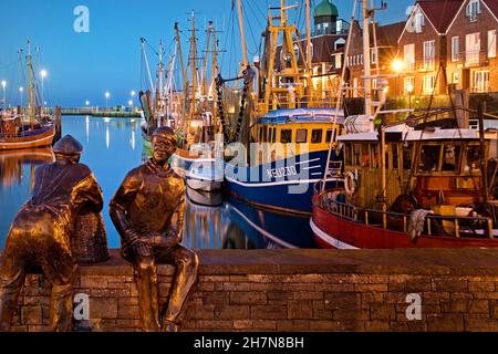 Porto di pesca di sera con pescatori giovani e vecchi, artista Hans-Christian Petersen, Neuharlingersiel, Frisia orientale, bassa Sassonia, Germania Foto Stock