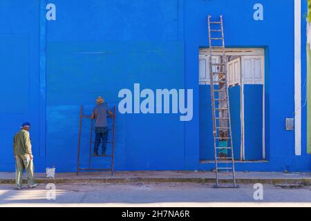 TRINIDAD, CUBA - 7 GENNAIO 2021: Lavoro cubano pittura fuori casa in blu il 7 gennaio 2021 a Trinidad. Le case a Cuba devono essere Foto Stock