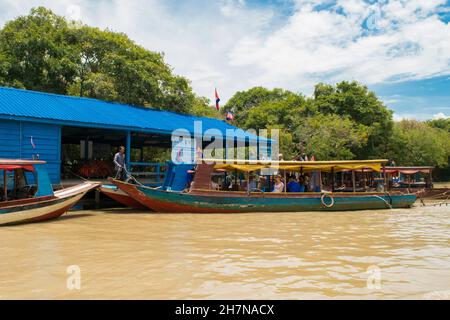 KAMPONG PHLUK, CAMBOGIA - 13 agosto 2017: Lunghe barche legate insieme e ormeggiate vicino al fiume riva del lago Tonle SAP, per il trasporto turistico a Kampong Phluk Foto Stock