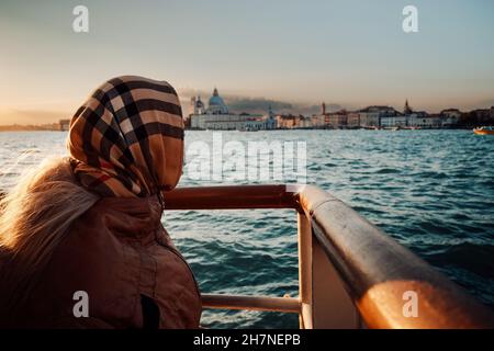 Signora anziana con una sciarpa in testa in piedi su un punto di vista a Venezia, Italia Foto Stock