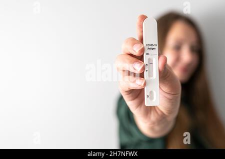 Test negativo sull'antigene rapido COVID-19 in presenza di una persona sfocata non riconoscibile con spazio di copia. Donna mostra il suo risultato del test. Viaggio durante il concetto di pandemia di coronavirus. Foto Stock