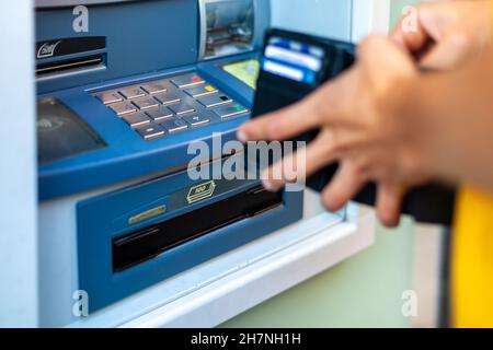 Prelevare contanti da un bancomat su una strada della città Foto Stock