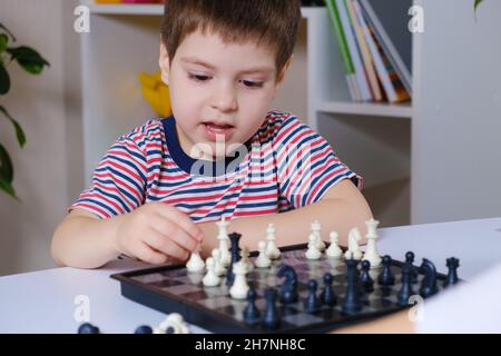 Un ragazzo prescolare gioca a scacchi, giochi da tavolo per bambini. Foto Stock