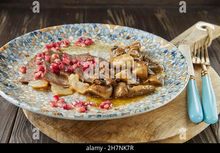 Arrosto di manzo con funghi e semi di melograno. Cucina gourmet francese. Foto Stock