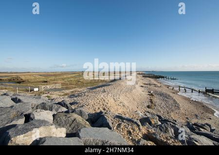 Le difese del mare abbandonate, l'erosione, i groynes di pietra, i ciottoli e le pietre, separando il mare e la riserva naturale di RSPB Medmerry. Vista sud-est verso Selsey, Foto Stock