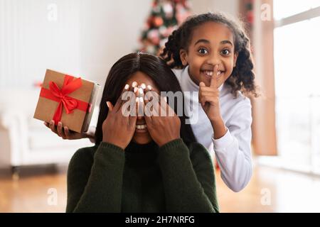 Regalo segreto. Felice famiglia nera festeggia il Natale Foto Stock