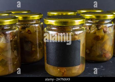 Chutney dopo la zucchina è cresciuto nel midollo. Diversi vasi sfondo nero paesaggio copyspace in alto nero etichetta. Foto Stock