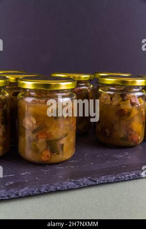 Chutney dopo la zucchina è cresciuto nel midollo. Diversi jars nero scuro sfondo ritratto. Foto Stock