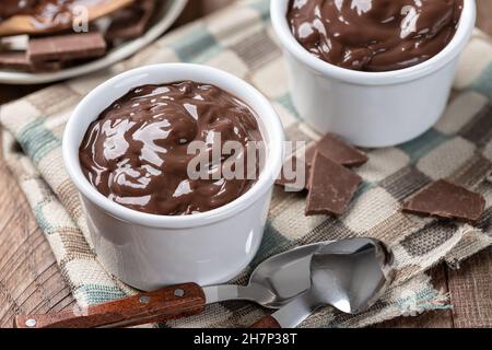 Primo piano di budino di cioccolato cremoso in una tazza bianca su un tovagliolo di stoffa Foto Stock