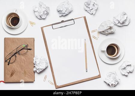 Carta sminuzzata sparsa, tazze vuote di caffè sul tavolo di un lavoratore creativo. Crisi creativa. Concetto di stress, problemi di salute mentale e mancanza di me Foto Stock