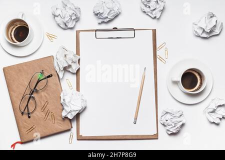 Carta sminuzzata sparsa, tazze vuote di caffè sul tavolo di un lavoratore creativo. Crisi creativa. Concetto di stress, problemi di salute mentale e mancanza di me Foto Stock