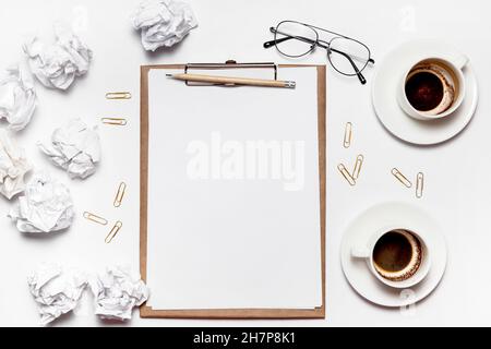 Carta sminuzzata sparsa, tazze vuote di caffè sul tavolo di un lavoratore creativo. Crisi creativa. Concetto di stress, problemi di salute mentale e mancanza di me Foto Stock