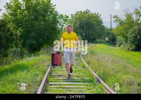 un uomo di mezza età in una t-shirt gialla corre lungo le rotaie Foto Stock