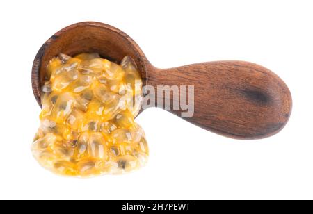 Semi di frutto della passione in cucchiaio di legno, isolato su sfondo bianco. Polpa di passionfrutto o maracuya, frutta esotica. Foto Stock