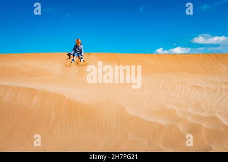 Un bambino ha giocato sulle dune di sabbia divertendosi con la libertà, lo spazio negativo, lo spazio di copia e colori intensi. Foto Stock