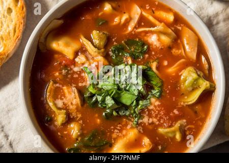 Zuppa italiana di tortellini fatta in casa con formaggio e basilico Foto Stock