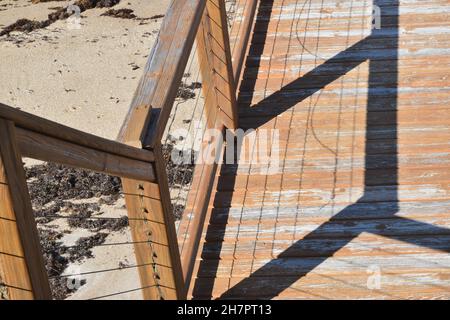 Cavi e ringhiere formano ombre sul legno. Foto Stock