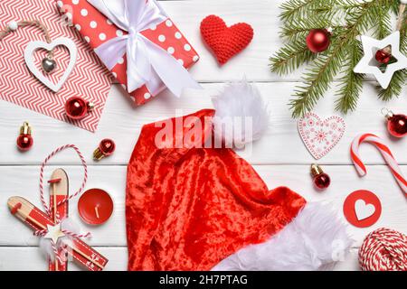 Vista dall'alto su uno sfondo di rami di abete, decorazioni natalizie, cappelli e regali su un tavolo bianco di legno.biglietto di auguri di Capodanno. Un mock-up di un Christm Foto Stock