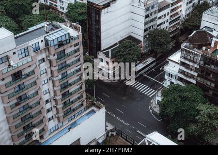 Una vista in drone dall'alto di un bivio con una zebra pedonale che attraversa una giornata piovosa in cielo con asfalto bagnato e un gruppo di abitazioni Foto Stock