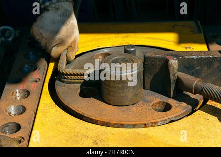 Macchina piegatrice per barrette nel sito. Preparazione di pezzi da aste di armatura per lavori in calcestruzzo. Macchina curvatrice per armatura nella costruzione Foto Stock