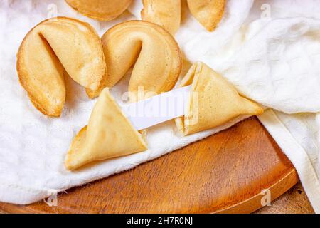 Biscotti di fortuna cinesi gialli appena sfornati con nota bianca all'interno su sfondo chiaro. Foto Stock