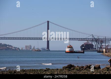 MADRID, SPAGNA - 30 settembre 2021: Il ponte sospeso del 25 aprile a Lisbona sul bel fiume Tago con navi sotto un cielo blu Foto Stock