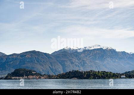 Vista dal Lago di Como alle case sulla costa sullo sfondo delle montagne. Bellagio, Italia Foto Stock