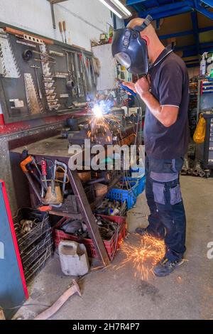 Saldatrice che lavora con la lancia elettrica in officina. Foto Stock