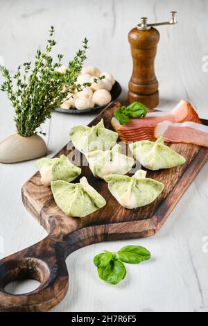 Gnocchi ripieni di prosciutto affumicato e funghi su tavola di legno Foto Stock