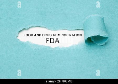 Testo stampato FDA Food and Drug Administration che appare dietro carta blu strappata. Foto Stock