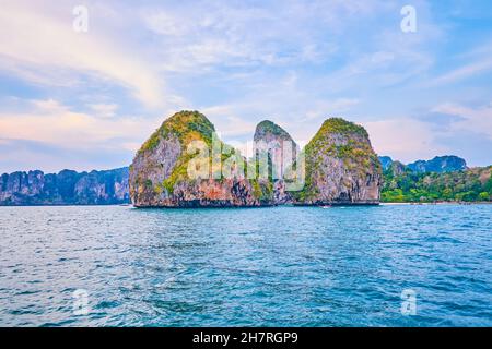 Gita in yacht lungo la costa rocciosa della Penisola di Railay con una vista sulle piccole isole Ko Nang e Ko Rang NOK, coperte di verde tropicale e bagnate da emeral Foto Stock