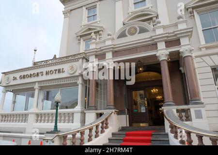 Una vista esterna dell'entrata del St George's Hotel con una grande scala con moquette rossa e lampadari nella lobby dietro. Foto Stock