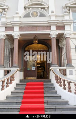 Una vista esterna dell'entrata del St George's Hotel con una grande scala con moquette rossa e lampadari nella lobby dietro. Foto Stock